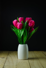 Red tulips in a vase black background