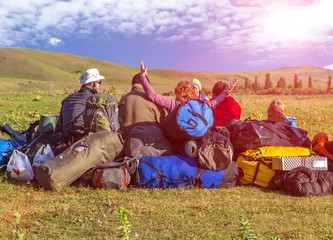 Jolly Company of Tourists Sitting on Large Heap of Travel Luggage on Green Meadow of Wild...