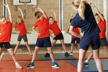 Teacher Taking Exercise Class In School Gym