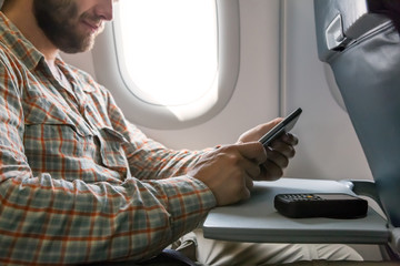 Hands of man browsing gadget in aircraft Person sitting inside airplane Window Seat Using...