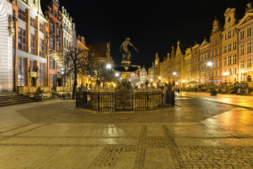 A closup of Neptune statue in Gdansk with colorful houses in the background, Poland, at night © janmiko