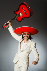 Funny mexican in suit holding guitar against gray