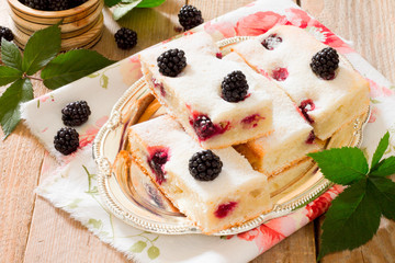 Cake cake with fresh blackberries on a wooden table