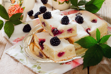 Cake cake with fresh blackberries on a wooden table