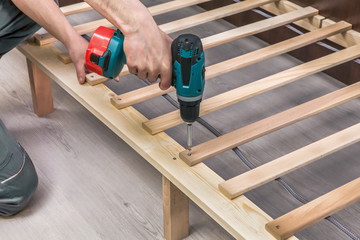 Wooden furniture assembling- woodworker screwing screws using a
