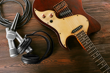 Naklejka premium Electric guitar with microphones and headphones on wooden table close up