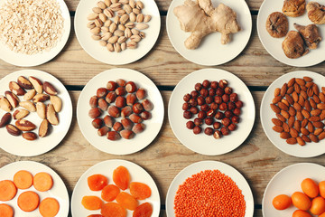 Different products on saucers on wooden table, top view