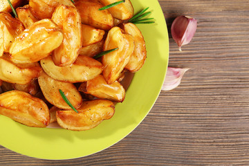 Baked potato wedges on wooden table, top view