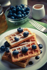 Sweet homemade waffles with forest berries and chocolate sauce on table background