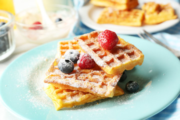 Sweet homemade waffles with forest berries on plate, on light background