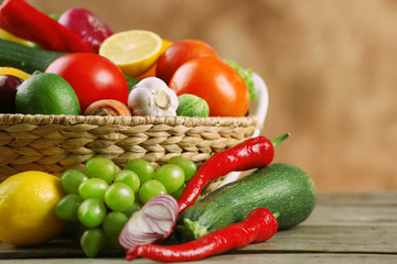Heap of fresh fruits and vegetables in basket on wooden table close up
