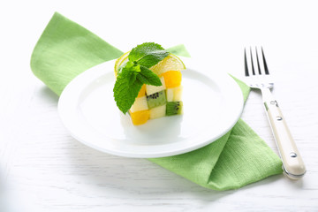 Fruit salad on plate, on light wooden background