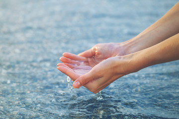 Female hands touching sea water