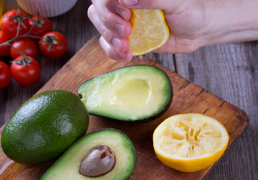 Man Hand Squeezing Lemon On Avocado.