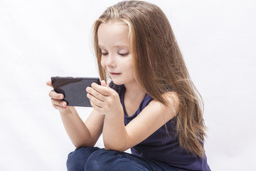 Fototapeta premium Little girl play with her smartphone