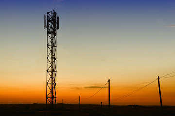 gsm tower and old telephone pylons silhouettes at dusk
