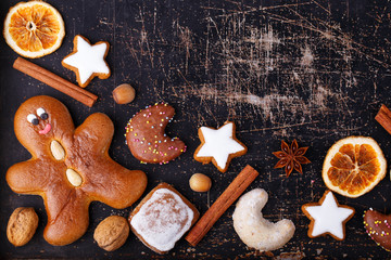 Ginger bread man, christmas cookies and spices on old dark scratched baking sheet 