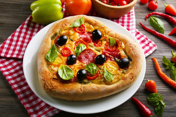 Heart shaped pizza served on plate on wooden background
