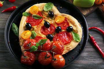 Heart shaped pizza on metal tray on wooden table