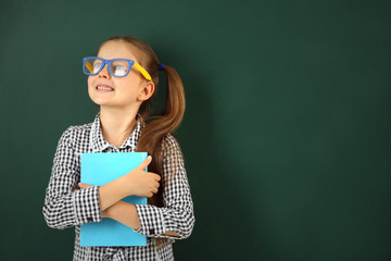 Beautiful little girl with book,  on blackboard background