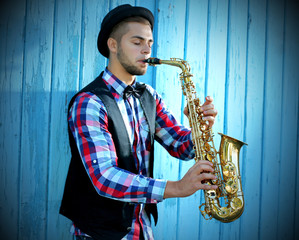 Young man playing on saxophone outside near the old wall