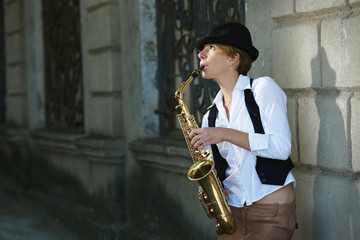Fototapeta na wymiar Girl with saxophone outside near the brick wall