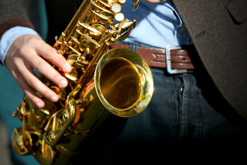 Obraz premium Young man with saxophone outside near the old painted wall