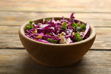Red cabbage and parsley salad in bowl on wooden table