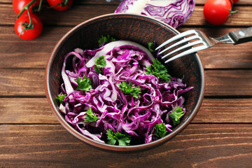 Red cabbage salad served in bowl on wooden background