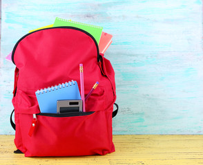 Naklejka premium Red bag with school equipment on wooden background