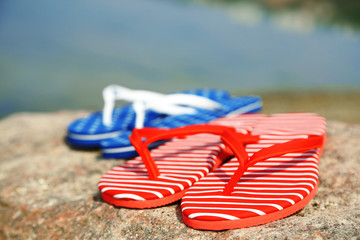 Bright flip-flops on stone, nature background