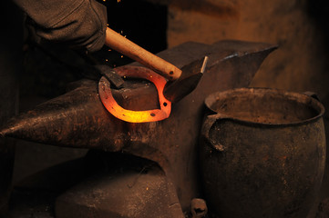 A blacksmith forging a horseshoe by a hammer