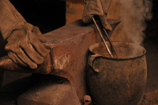A blacksmith cooling a horseshoe in a pot - Powered by Adobe