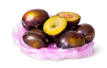 Whole and half violet plums in plastic bag