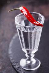 Shot of vodka with chili peppers on a black background.selective focus
