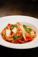 Spaghetti with tomato, parmesan and basil served in a white plate