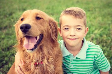 Cute little boy hugging his golden retriever pet dog