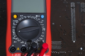 Fototapeta premium Red multimeter on motherboard background