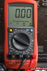 Red multimeter on motherboard background