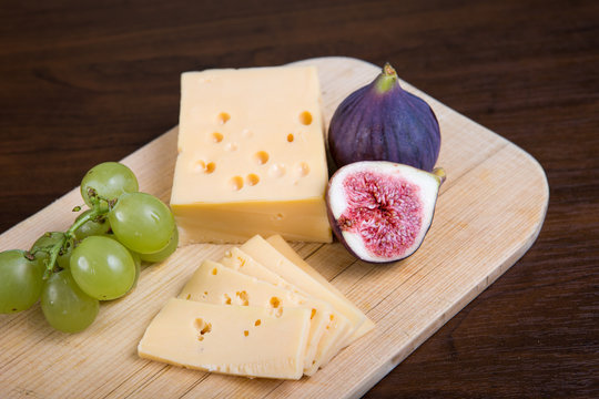 Yellow cheese and fresh figs on the wooden cutting board