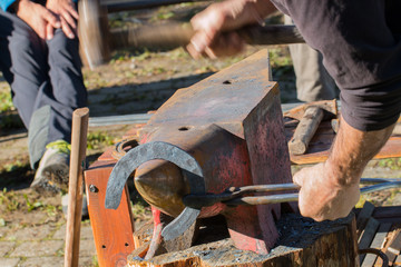 Blacksmith forging an horse shoe on anvil