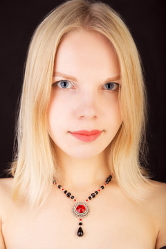 Portrait of a young beautiful lady with necklace isolated over black background