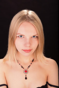 Portrait of a young beautiful lady with necklace isolated over black background