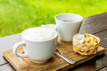 A cappuccino and some biscuits on the table and background lands