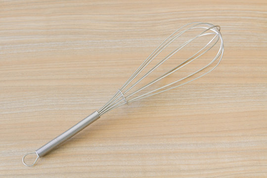 stainless balloon whisk on wooden background