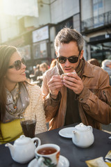 Backlit shoot. Trendy couple having fun and sitting at a terrace