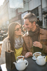 Backlit shoot. Trendy couple having fun and sitting at a terrace