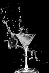 Cocktail glass with splashes isolated on a black background.