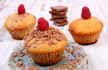 Fresh baked muffins with raspberries and chocolate on wooden background, delicious dessert