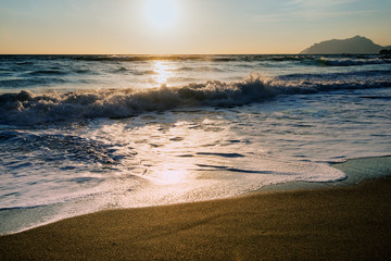 Foamy water  on sandy beach shore at sunset, Corfu, Greece. Amazing sandy beach with sea weeds and  clouds, Corfu, Greece.